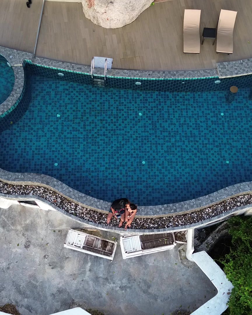 Cenital de una piscina de resort con tumbonas y vegetación